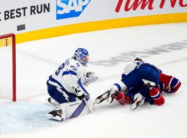 Mikhail Sergachev of the Tampa Bay Lightning falls on top of Artturi Lehkonen of the Montreal Canadiens as Andrei Vasilevskiy tends net during the...