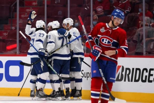 Jesperi Kotkaniemi of the Montreal Canadiens skates by as Nikita Kucherov of the Tampa Bay Lightning celebrates with teammates after scoring against...