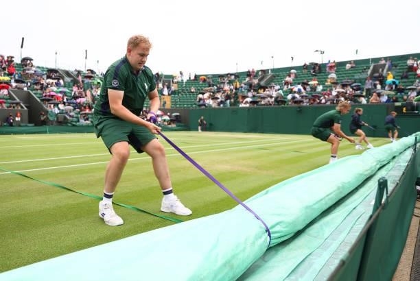 Ground staff bring the covers on as rain delays play on Day Six of The Championships - Wimbledon 2021 at All England Lawn Tennis and Croquet Club on...