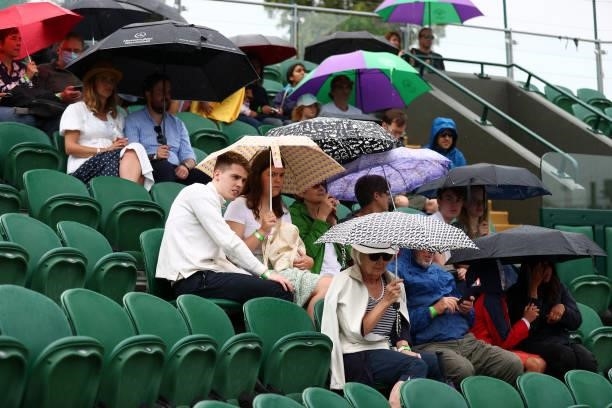 Spectators are seen with umbrella's as rain delays play on Day Six of The Championships - Wimbledon 2021 at All England Lawn Tennis and Croquet Club...