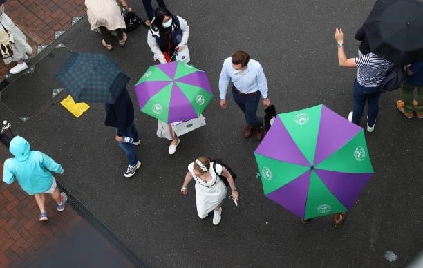 Spectators are seen with umbrellas as rain delays play on Day Six of The Championships - Wimbledon 2021 at All England Lawn Tennis and Croquet Club...