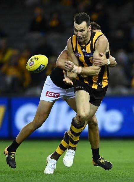 Jonathon Ceglar of the Hawks handballs whilst being tackled by Steven Motlop of the Power during the round 16 AFL match between Hawthorn Hawks and...