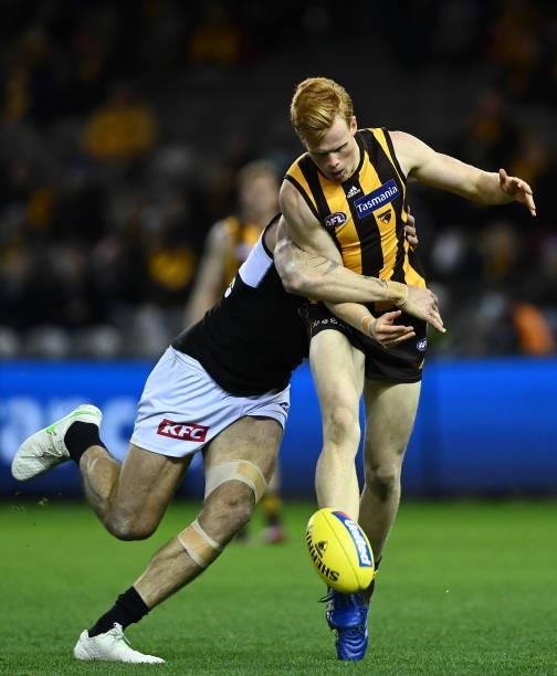 Damon Greaves of the Hawks kicks whilst being tackled by Charlie Dixon of the Power during the round 16 AFL match between Hawthorn Hawks and Port...