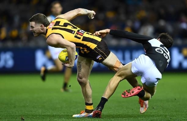 Blake Hardwick of the Hawks handballs whilst being tackled by Connor Rozee of the Power during the round 16 AFL match between Hawthorn Hawks and Port...