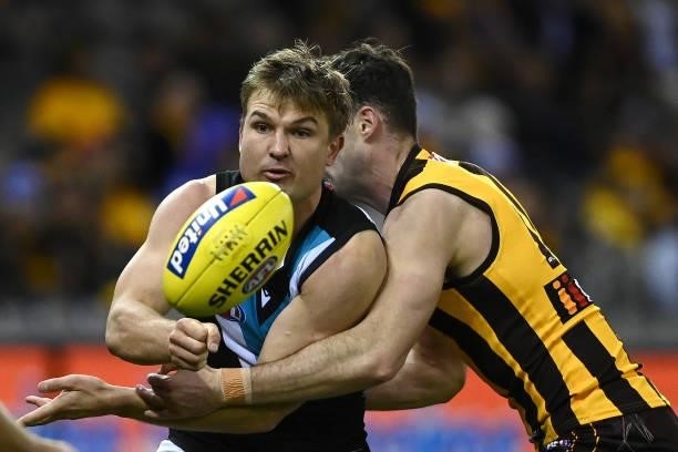Ollie Wines of the Power handballs whilst being tackled during the round 16 AFL match between Hawthorn Hawks and Port Adelaide Power at Marvel...
