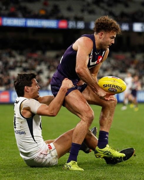 Griffin Logue of the Dockers handballs whilst being tackled by Jack Silvagni of the Blues during the round 16 AFL match between Fremantle Dockers and...
