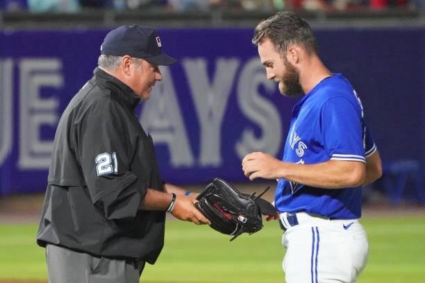 Nick Allgeyer of the Toronto Blue Jays shows his equipment to an umpire during the game against the Tampa Bay Rays at Sahlen Field on July 2, 2021 in...