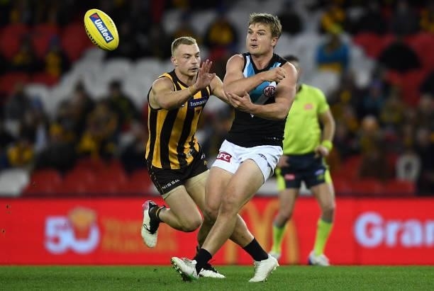 Ollie Wines of the Power handballs whilst being tackled by James Worpel of the Hawks during the round 16 AFL match between Hawthorn Hawks and Port...