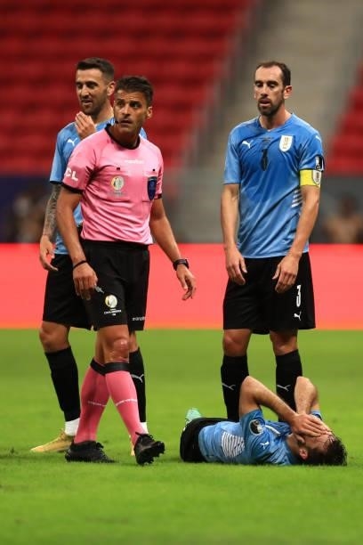 Referee Jesus Gil Manzano checks on Matias Viña of Uruguay who suffered an injury during a quarter-final match of Copa America Brazil 2021 between...