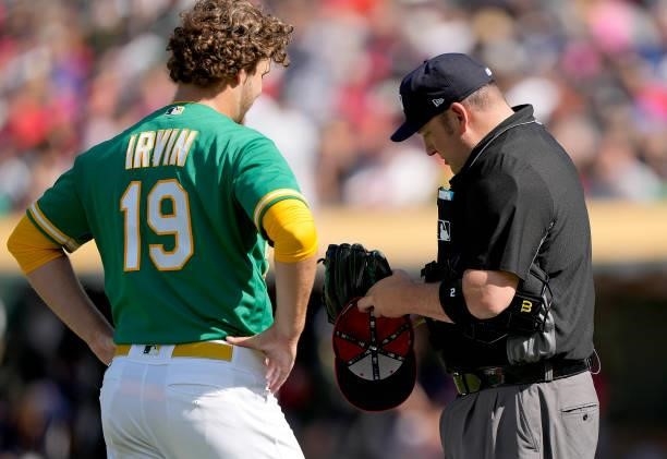 Home plate umpire Dan Bellino checks the hat and glove of pitcher Cole Irvin of the Oakland Athletics in the second inning against the Boston Red Sox...