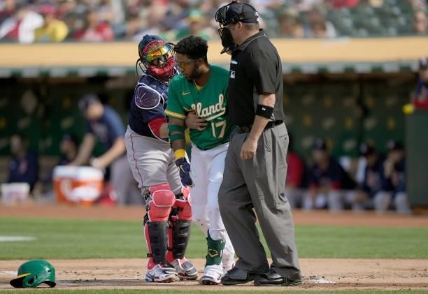 Elvis Andrus of the Oakland Athletics is helped up off the ground by Christian Vazquez of the Boston Red Sox and home plate umpire Dan Bellino after...