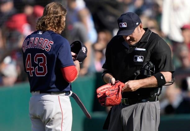 Home plate umpire Dan Bellino checks the pants and glove of pitcher Garrett Richards of the Boston Red Sox for illegal substances at the end of the...