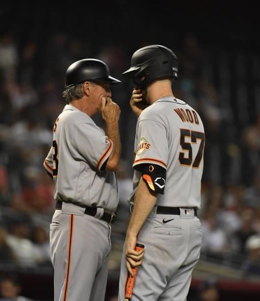 Alex Wood of the San Francisco Giants talks with third base coach Ron Wotus prior to stepping into the batters box against the Arizona Diamondbacks...