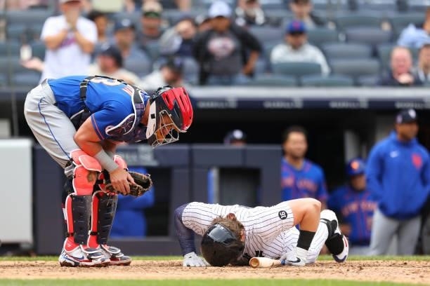 Luke Voit of the New York Yankees lies on the ground after being hit by a pitch during the sixth inning as catcher James McCann of the New York Mets...