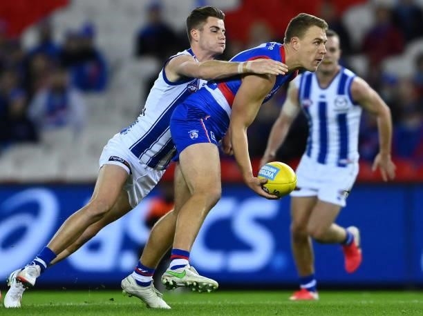 Jackson Macrae of the Bulldogs handballs whilst being tackled by Bailey Scott of the Kangaroos during the round 16 AFL match between Western Bulldogs...