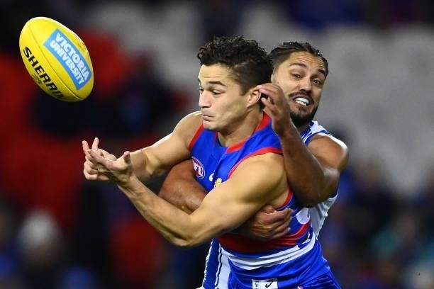 Riley Garcia of the Bulldogs handballs whilst being tackled by Aaron Hall of the Kangaroos during the round 16 AFL match between Western Bulldogs and...