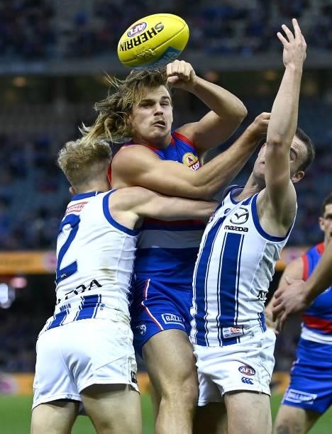 Bailey Smith of the Bulldogs handballs whilst being tackled by Jaidyn Stephenson of the Kangaroos during the round 16 AFL match between Western...