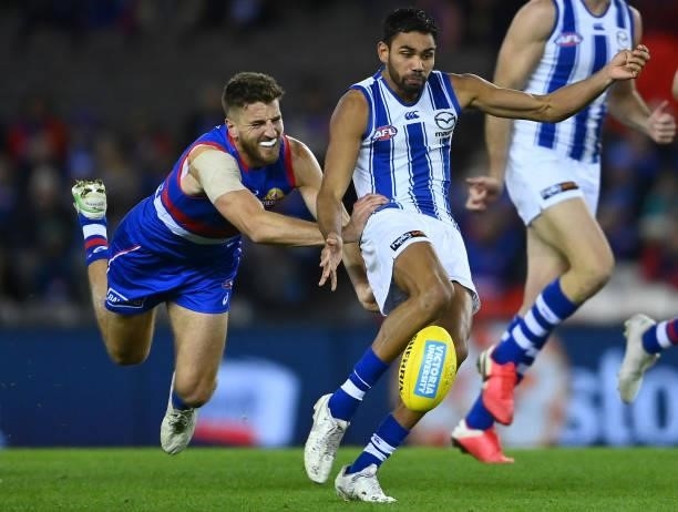 Tarryn Thomas of the Kangaroos kicks whilst being tackled by Marcus Bontempelli of the Bulldogs during the round 16 AFL match between Western...