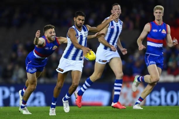 Tarryn Thomas of the Kangaroos kicks whilst being tackled by Marcus Bontempelli of the Bulldogs during the round 16 AFL match between Western...