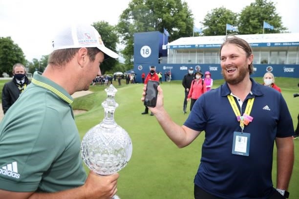 Lucas Herbert of Australia holds the winners trophy as he gets a call from home after the final round of The Dubai Duty Free Irish Open at Mount...
