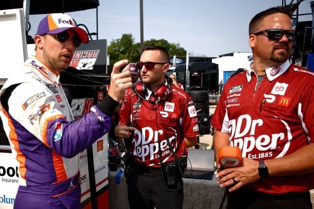 Denny Hamlin, driver of the FedEx Freight Toyota, and co-owner of 23XI Racing speaks with crew members of the Dr. Pepper Toyota, during qualifying...