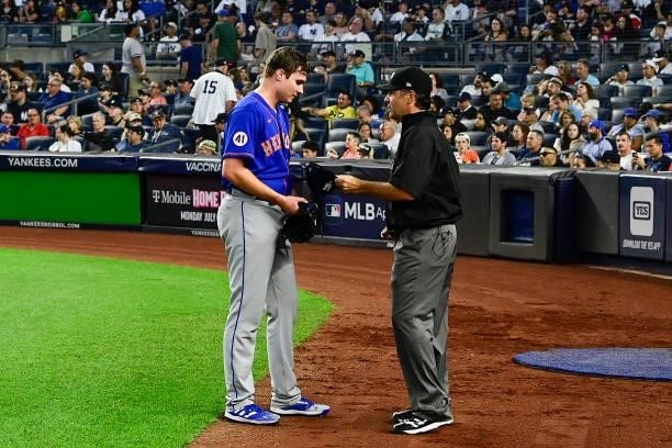 Corey Oswalt of the New York Mets has his equipment checked for foreign substances by umpire James Hoye following the fourth inning during game two...