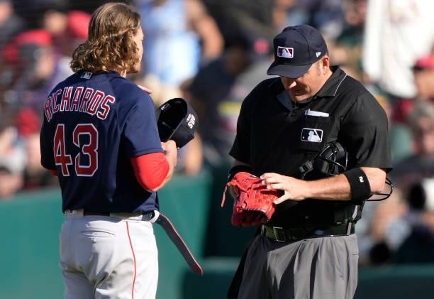 Home plate umpire Dan Bellino checks the pants and glove of pitcher Garrett Richards of the Boston Red Sox for illegal substance at the end of the...