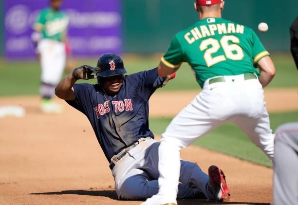 Rafael Devers of the Boston Red Sox slides under Matt Chapman of the Oakland Athletics into third base safe in the top of the fourth inning at...