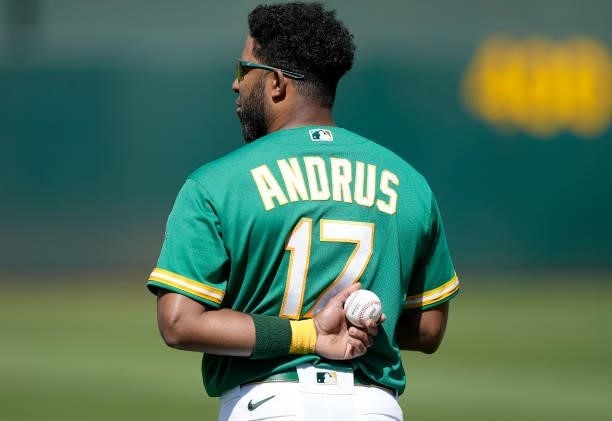 Elvis Andrus of the Oakland Athletics with one hand behind his back holding a baseball stands for the National Anthem prior to the start of his game...