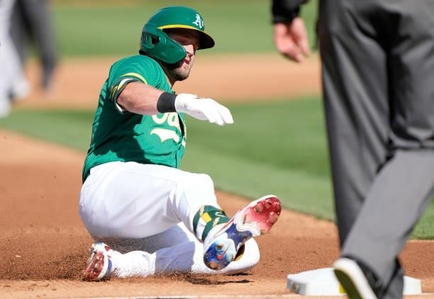 Seth Brown of the Oakland Athletics slides in to third base with an RBI triple against the Boston Red Sox in the bottom of the second inning at...