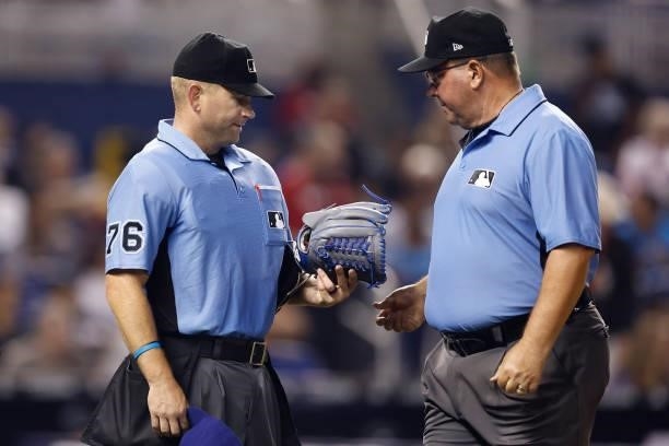 Umpire Mike Muchlinski and umpire Sam Holbrook talk about Edwin Uceta glove during the seventh inning against the Miami Marlins at loanDepot park on...