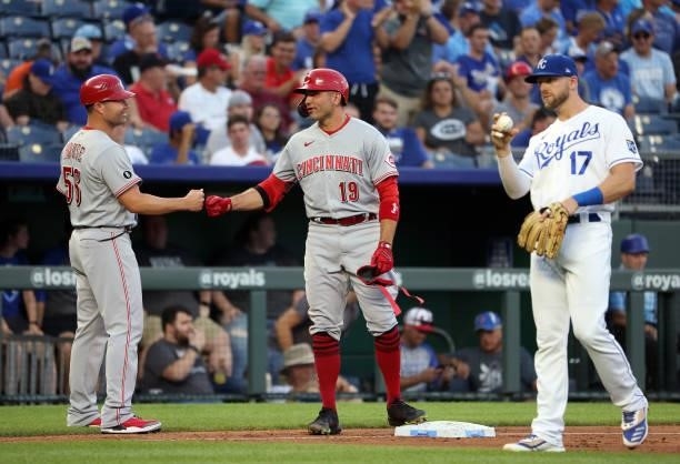 Joey Votto of the Cincinnati Reds fist-bumps third base coach J.R. House after hitting a 2-RBI triple during the 3rd inning of the game against the...