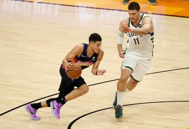 Devin Booker of the Phoenix Suns drives to the basket against Brook Lopez of the Milwaukee Bucks during the first quarter in Game One of the NBA...