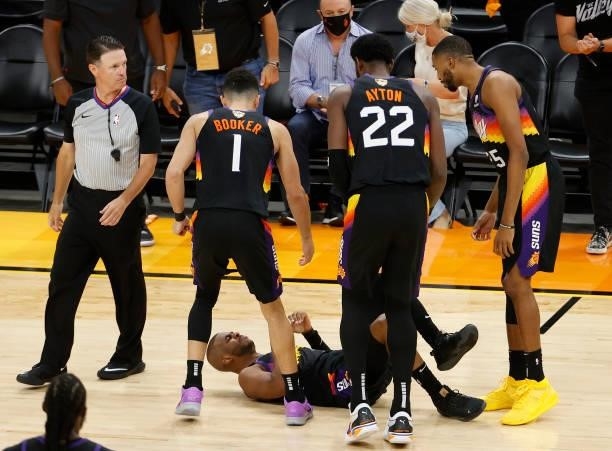 Chris Paul of the Phoenix Suns is is looked at by teammates Devin Booker, Deandre Ayton and Mikal Bridges after going down against the Milwaukee...