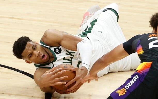 Giannis Antetokounmpo of the Milwaukee Bucks grabs a loose ball against Cameron Johnson of the Phoenix Suns during the second half in Game One of the...
