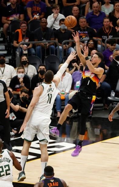 Devin Booker of the Phoenix Suns shoots against Brook Lopez of the Milwaukee Bucks during the first half in Game One of the NBA Finals at Phoenix...