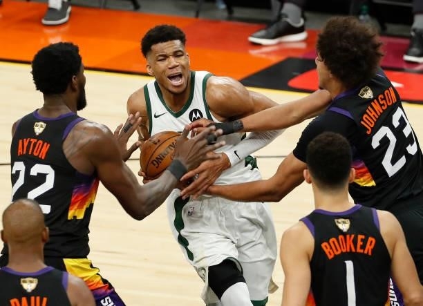 Giannis Antetokounmpo of the Milwaukee Bucks is pressured by Deandre Ayton and Cameron Johnson of the Phoenix Suns during the second half in Game One...