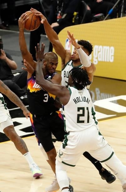Chris Paul of the Phoenix Suns is pressured by Giannis Antetokounmpo and Jrue Holiday of the Milwaukee Bucks during the second half in Game One of...