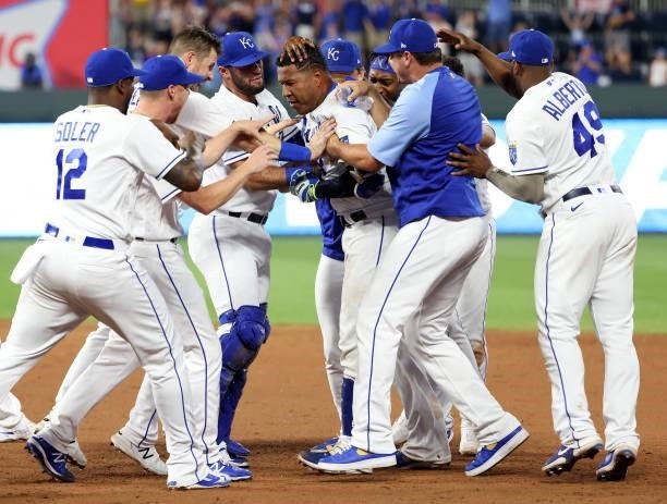 Teammates swarm Salvador Perez of the Kansas City Royals after Perez hit the game-winning wal-off single to defeat the Cincinnati Reds 7-6 and win...
