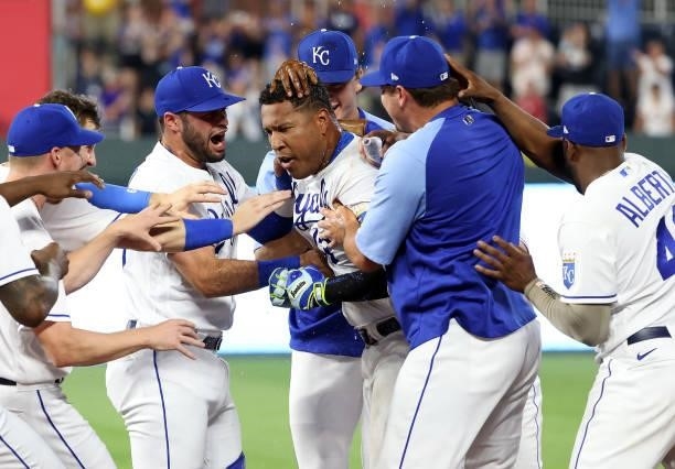 Teammates swarm Salvador Perez of the Kansas City Royals after Perez hit the game-winning walk-off single to defeat the Cincinnati Reds 7-6 and win...