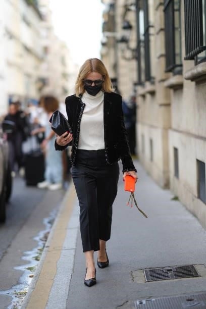 Guest wears sunglasses, a white turtleneck pullover, a black jacket, black pants, a black shiny leather handbag from Chanel, gold rings, black shiny...