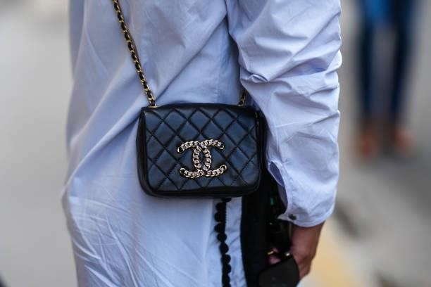 Guest wears a pale blue shirt, a black shiny quilted leather Chanel crossbody bag, outside Armani, during Paris Fashion Week - Haute Couture...