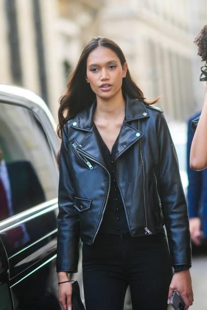 Model wears a black shiny leather biker jacket, black V-neck buttoned t-shirt, black pants, outside Armani, during Paris Fashion Week - Haute Couture...