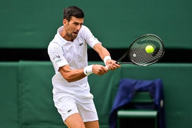 Novak Djokovic of Serbia hits a backhand against Marton Fucsovics of Hungary in the quarter finals of the gentlemen's singles during Day Nine of The...