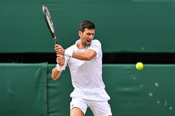 Novak Djokovic of Serbia hits a backhand against Marton Fucsovics of Hungary in the quarter finals of the gentlemen's singles during Day Nine of The...