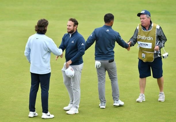 Xander Schauffele of the United States, Tommy Fleetwood and Tyrrell Hatton of England finish their round on the 18th green during Day Two of the...