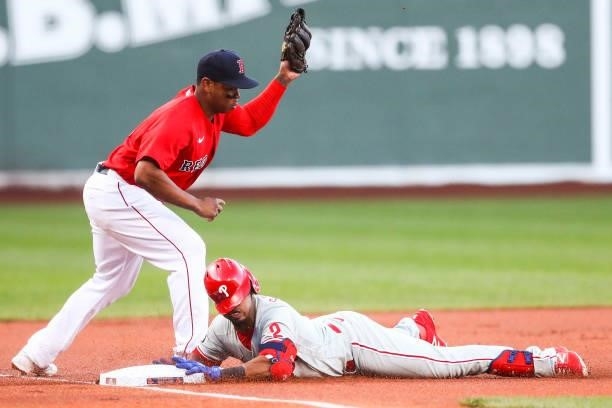 Jean Segura of the Philadelphia Phillies slides safely into third base under the tag of Rafael Devers of the Boston Red Sox after hitting a triple in...