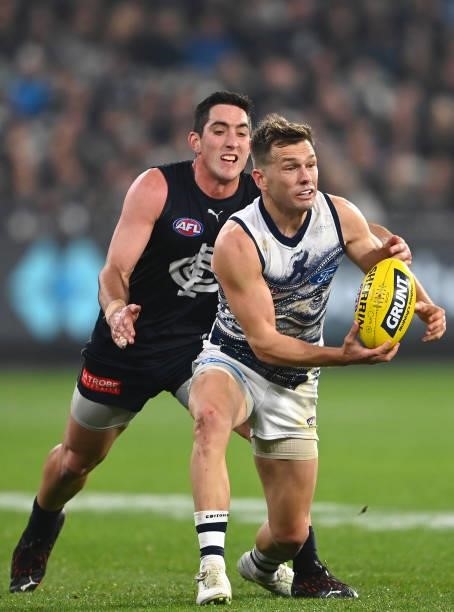 Shaun Higgins of the Cats handballs whilst being tackled by Jacob Weitering of the Blues during the round 17 AFL match between Carlton Blues and...