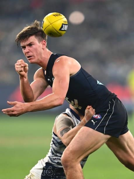 Paddy Dow of the Blues handballs whilst being tackled by Brandan Parfitt of the Cats during the round 17 AFL match between Carlton Blues and Geelong...