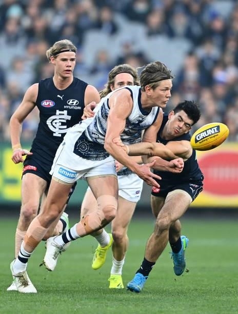 Rhys Stanley of the Cats handballs whilst being tackled by Matthew Kennedy of the Blues during the round 17 AFL match between Carlton Blues and...